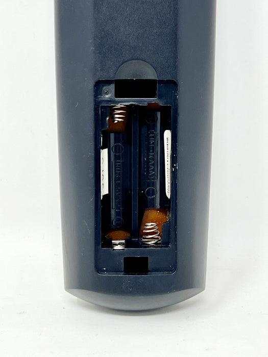 Close-up of the back of a dark blue remote control showing the battery compartment with two batteries inserted.