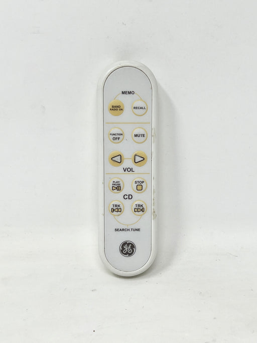 A white GE remote control with gold and black buttons, photographed against a plain off-white background.