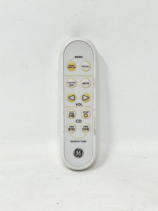 A white GE remote control with gold and black buttons, photographed against a plain off-white background.