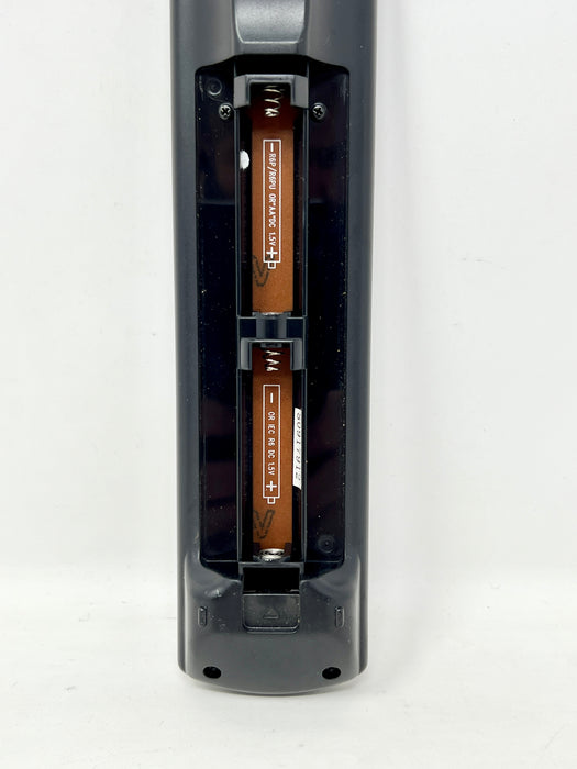 A close-up of a black cylindrical electronic device with its battery compartment open, showing two copper-colored batteries inserted vertically against a plain white background.
