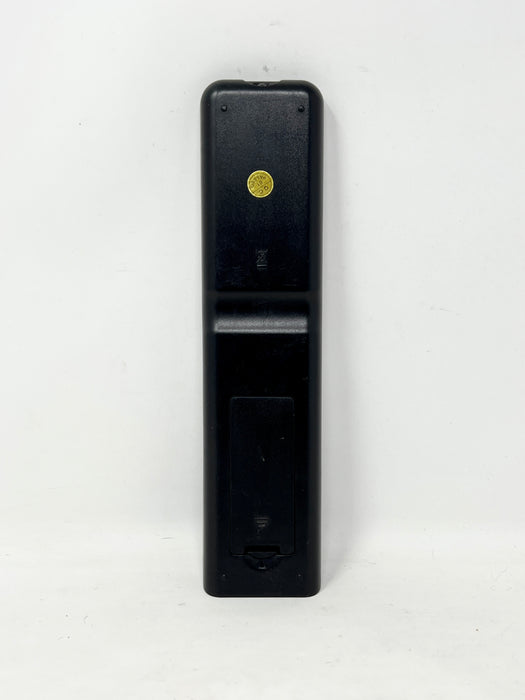 A black plastic remote control battery cover or back panel with a small gold circular detail, shown vertically against a plain white background.