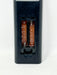 A close-up of a black plastic battery compartment cover with the back panel removed, showing two AA batteries installed inside. White printed text on the batteries reads 'UM-4 AAA IEC R03 1.