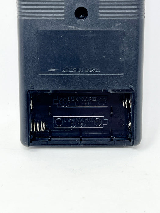 Close-up of the back of a black plastic battery-operated device with the battery compartment cover removed, showing spring-loaded contacts and embossed text including 'MADE IN JAPAN'.
