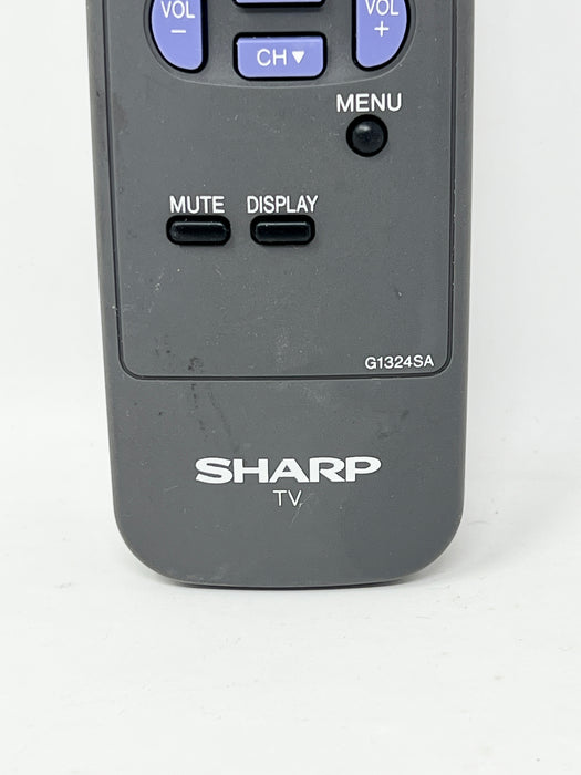 Close-up of a dark gray Sharp TV remote control showing the top buttons and controls, including VOL +/-, CH, MENU, MUTE, and DISPLAY.
