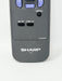 Close-up of a dark gray Sharp TV remote control showing the top buttons and controls, including VOL +/-, CH, MENU, MUTE, and DISPLAY.