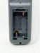 Close-up of the back of a gray remote control showing the battery compartment with the cover removed, on a white background.
