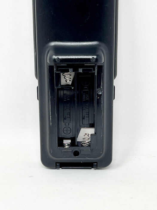 Close-up of the battery compartment cover of a black electronic device, showing the interior battery slots and terminals on a white background.