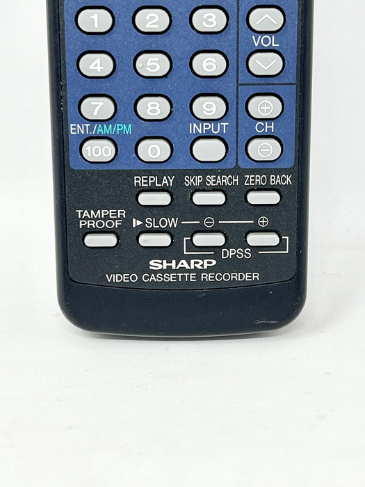 A close-up of a black and blue Sharp Video Cassette Recorder remote control, showing the number pad and various control buttons.