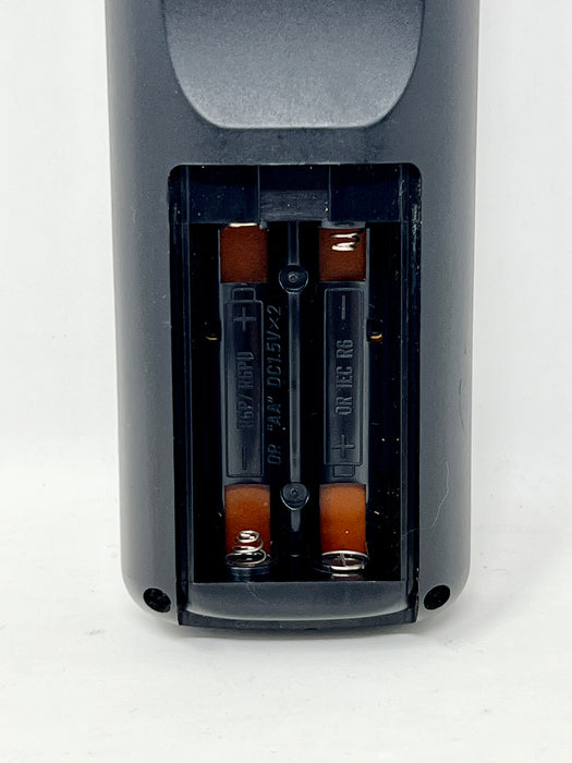 Close-up of the battery compartment of a dark gray remote control, showing two AA batteries inserted inside.