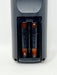 Close-up of the battery compartment of a dark gray remote control, showing two AA batteries inserted inside.