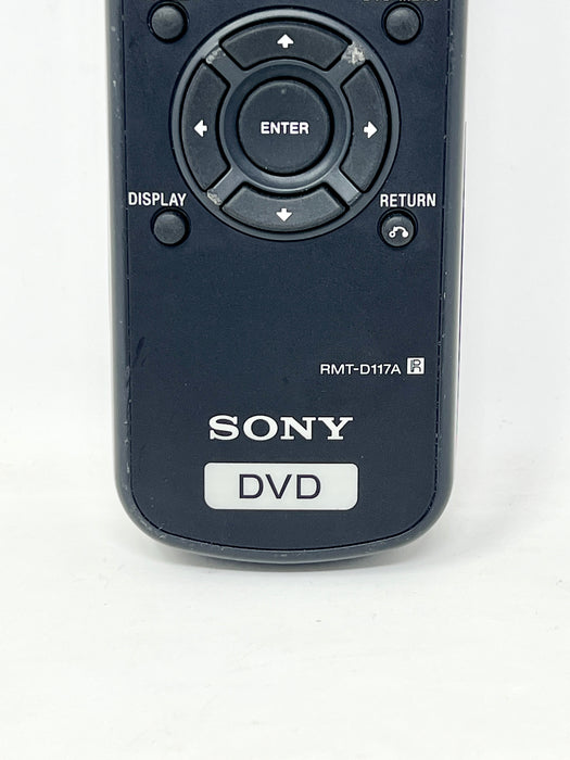 A close-up of a Sony DVD remote control, model RMT-D117A, featuring a dark blue plastic body with white text and a directional pad.