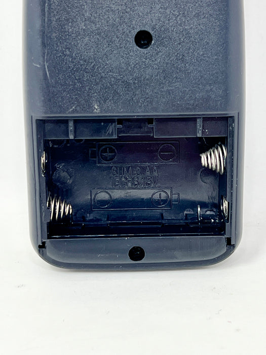 Close-up of the back of a dark blue-gray remote control showing the battery compartment with exposed spring batteries inside.