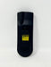 The back of a black plastic remote control with a yellow and black caution label, photographed against a plain white background.