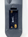 Close-up of the back of a black remote control showing the battery compartment with exposed gold-colored terminals and white battery contacts.